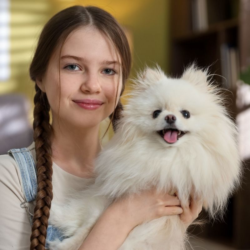 Girl holding dog, smiling